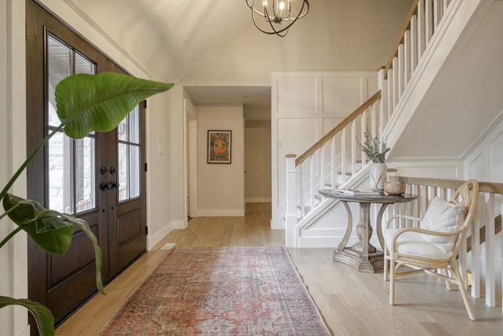Inviting, modern entryway with a warm colour palette and white staircase.