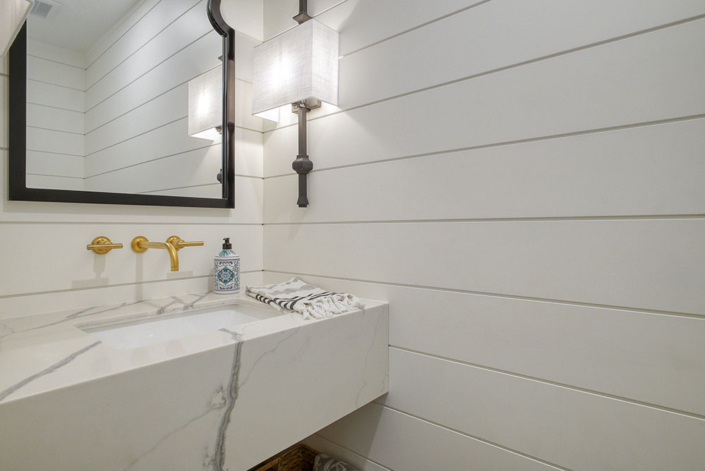 A beautiful contemporary sink in a bathroom with white panel walls.